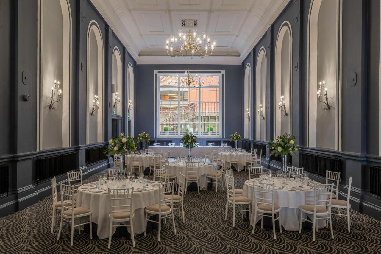 Hotel The Grand Hove Esterno foto The photo depicts an elegant banquet or event space. It features multiple round tables arranged throughout the room, each dressed with white tablecloths. Centerpieces with flowers are placed on each table, enhancing the decor. The room has high ceili
