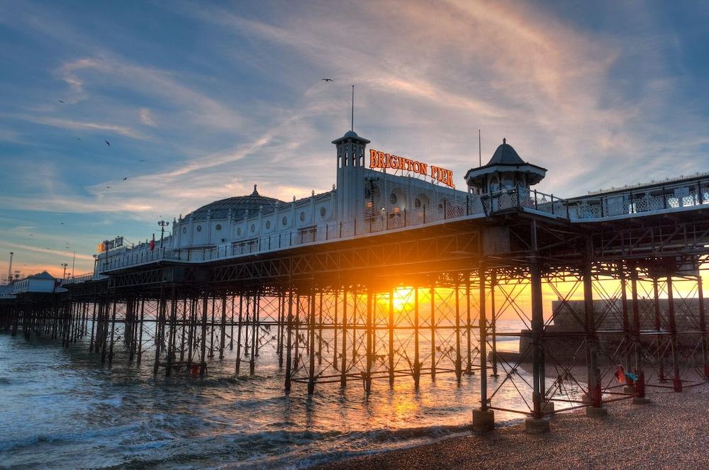 Hotel The Grand Hove Esterno foto The photo depicts a beautiful seaside pier, likely at sunset. The pier has a classic architectural style with a large, decorative building at its end, featuring a sign that may read "Brighton Pier." The structure is supported by numerous wooden pilla