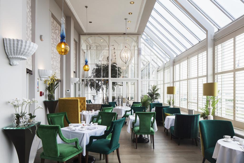 Hotel The Grand Hove Esterno foto The image shows a stylish restaurant interior characterized by a mix of modern and elegant design elements. The space features large windows that allow plenty of natural light, creating a bright and inviting atmosphere. 

The tables are set with whit