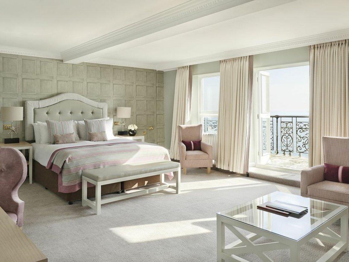 Hotel The Grand Hove Esterno foto The photo shows a spacious and elegantly designed hotel bedroom. The room features a large bed with a plush headboard, dressed in soft bedding. There are two comfortable armchairs in the corner, complemented by a small table in front of them. The roo