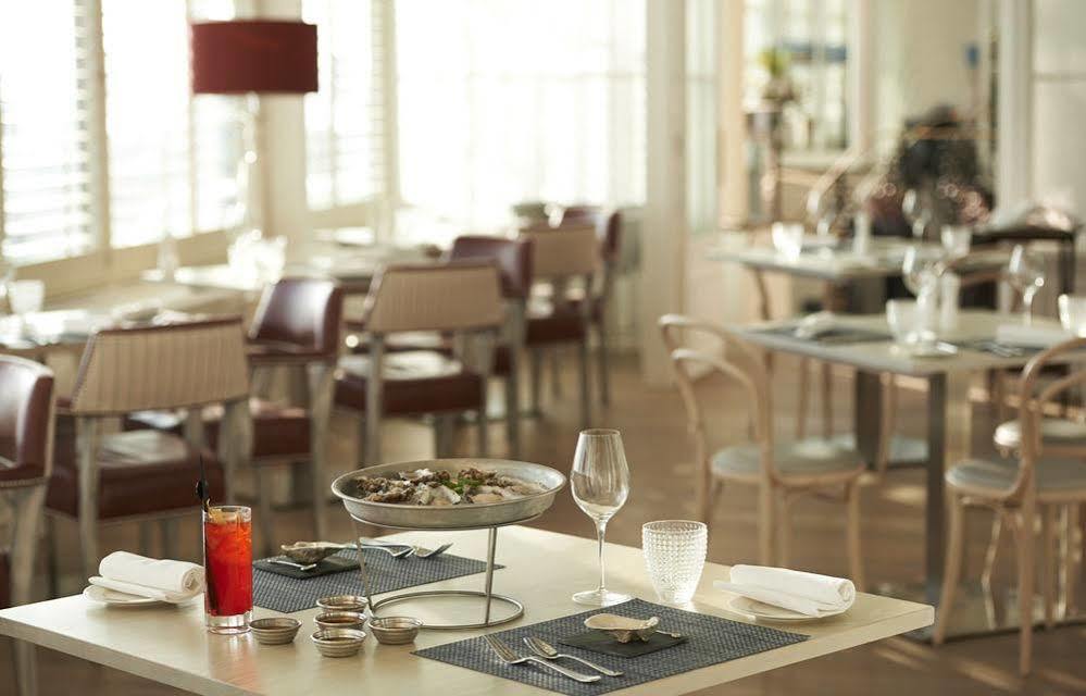 Hotel The Grand Hove Esterno foto The image shows a dining area in a restaurant with a modern and elegant design. There is a table set with several items, including a large dish of food on a stand, which appears to contain seafood or shellfish. Next to it, there are small dishes, pos