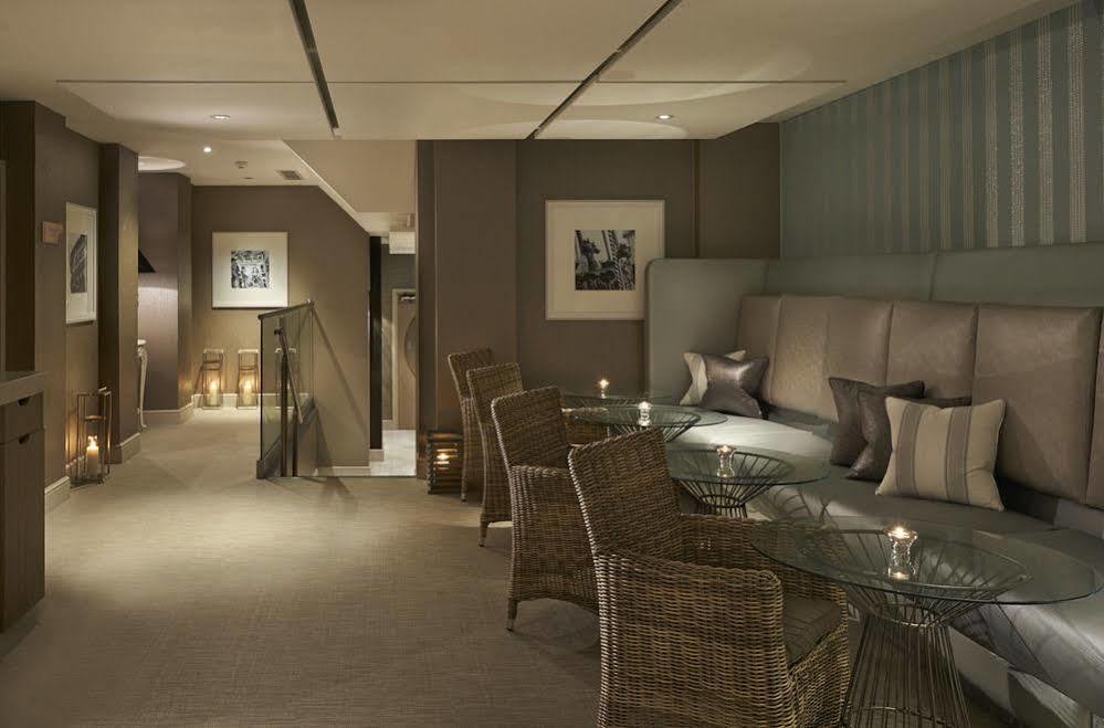 Hotel The Grand Hove Esterno foto The photo shows a stylish and modern interior space, likely a lounge or sitting area. It features neutral color tones, with soft lighting that creates a warm ambiance. There are several comfortable-looking chairs made of woven material around a glass