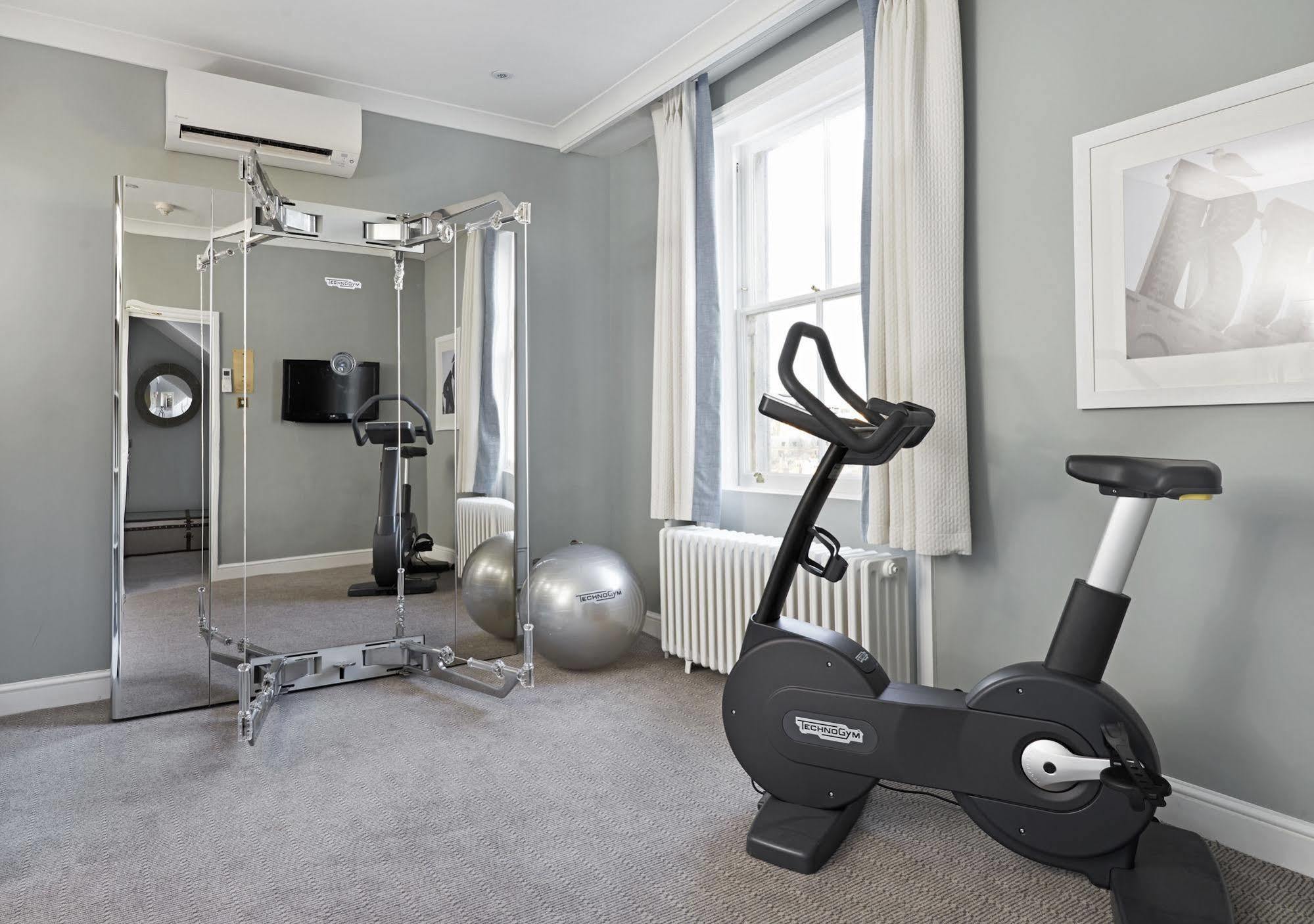 Hotel The Grand Hove Esterno foto The photo depicts a small home gym or fitness area. It features a stationary exercise bike on the right side and gym mirrors mounted on the left wall. There are also two exercise balls on the floor, providing options for balance and core exercises. T