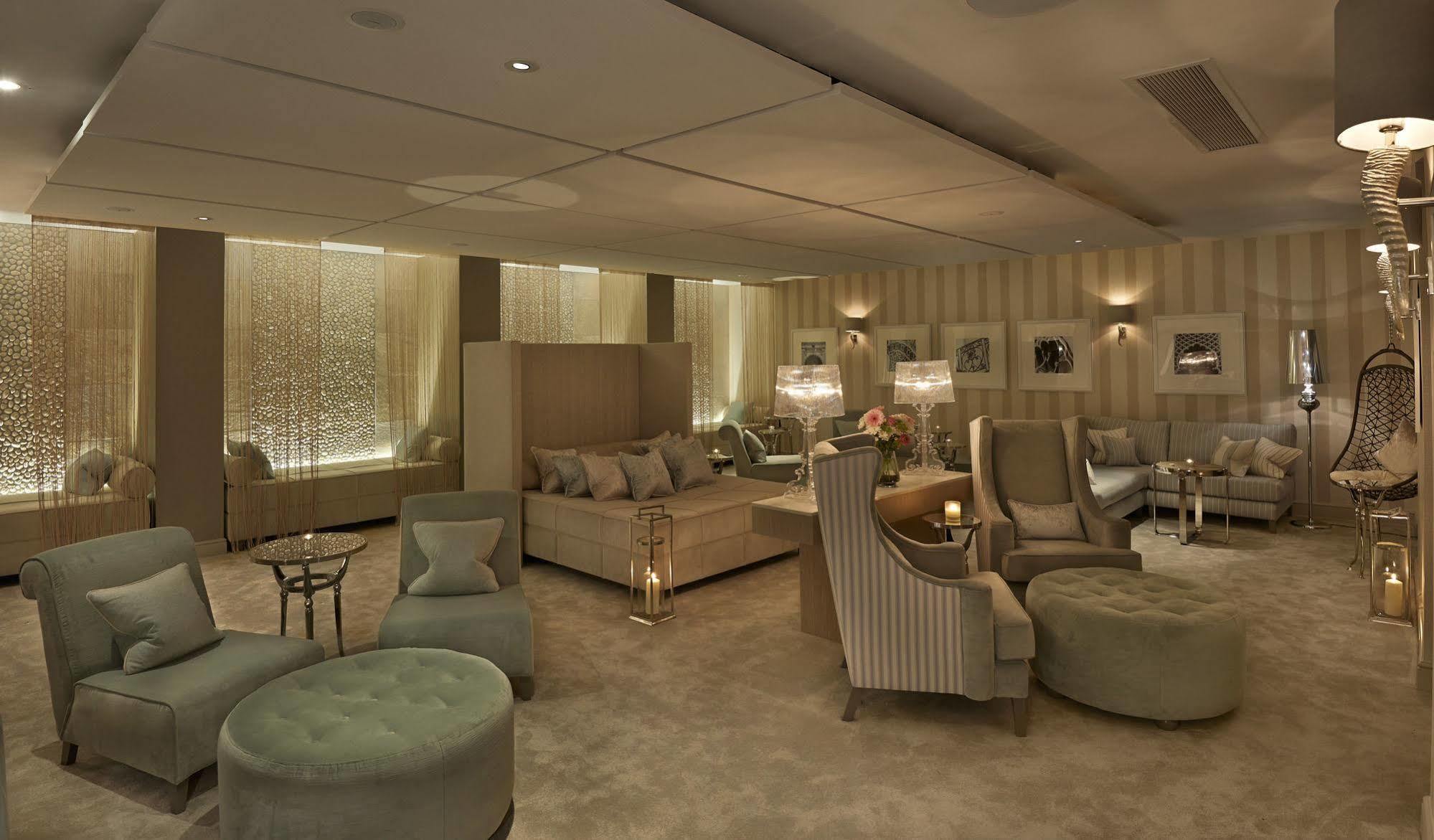 Hotel The Grand Hove Esterno foto The photo showcases a luxurious lounge or living area. The room features a plush, warm color palette with beige and soft green tones. There are several comfortable seating options, including a large sectional couch, armchairs, and ottomans. Elegant t