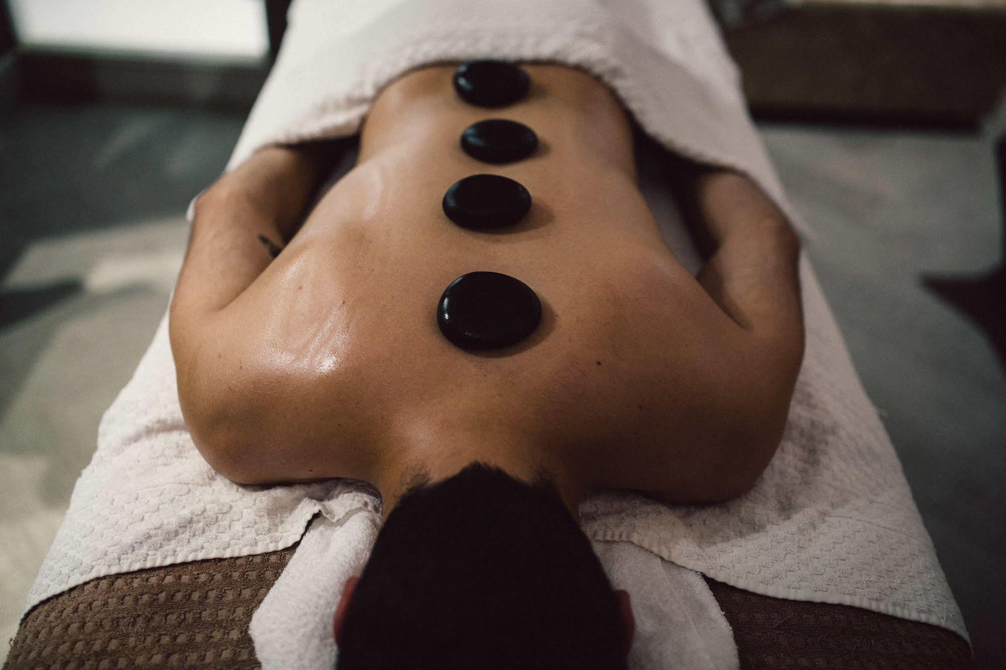 Hotel The Grand Hove Esterno foto The photo shows a person lying on a massage table with their back exposed. They are covered with a white towel, and there are several smooth, dark stones placed strategically along their spine. The setting appears to be a spa or wellness center, sugg