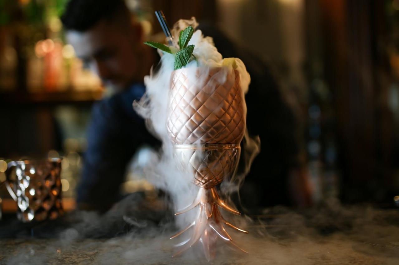 Hotel The Grand Hove Esterno foto The photo shows a beautifully crafted cocktail presented in a cup designed to look like a pineapple. The drink is topped with a fluffy white garnish and decorated with green mint leaves. There is a mist or smoke effect around the base of the cup, cre