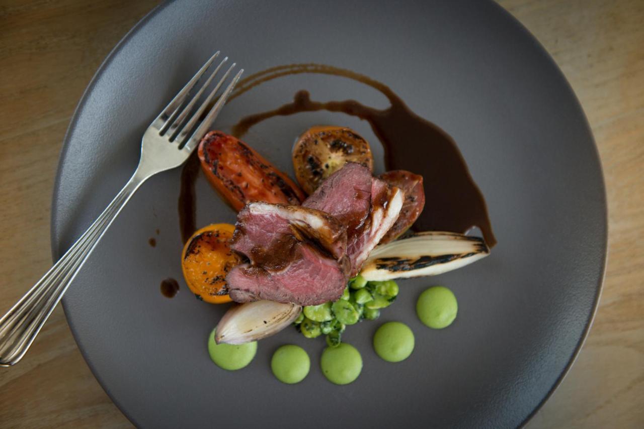 Hotel The Grand Hove Esterno foto The photo shows a plate of gourmet food, elegantly presented on a dark plate. It features slices of meat, likely a tender cut, topped with a rich sauce. Accompanying the meat are roasted vegetables, including carrots and possibly other root vegetable